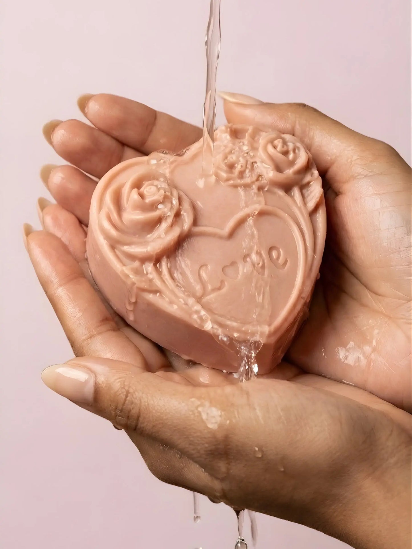 AMOREA heart soap with sculpted roses held under flowing water, natural luxury rose geranium vanilla soap from Deos Co Valentine’s Collection