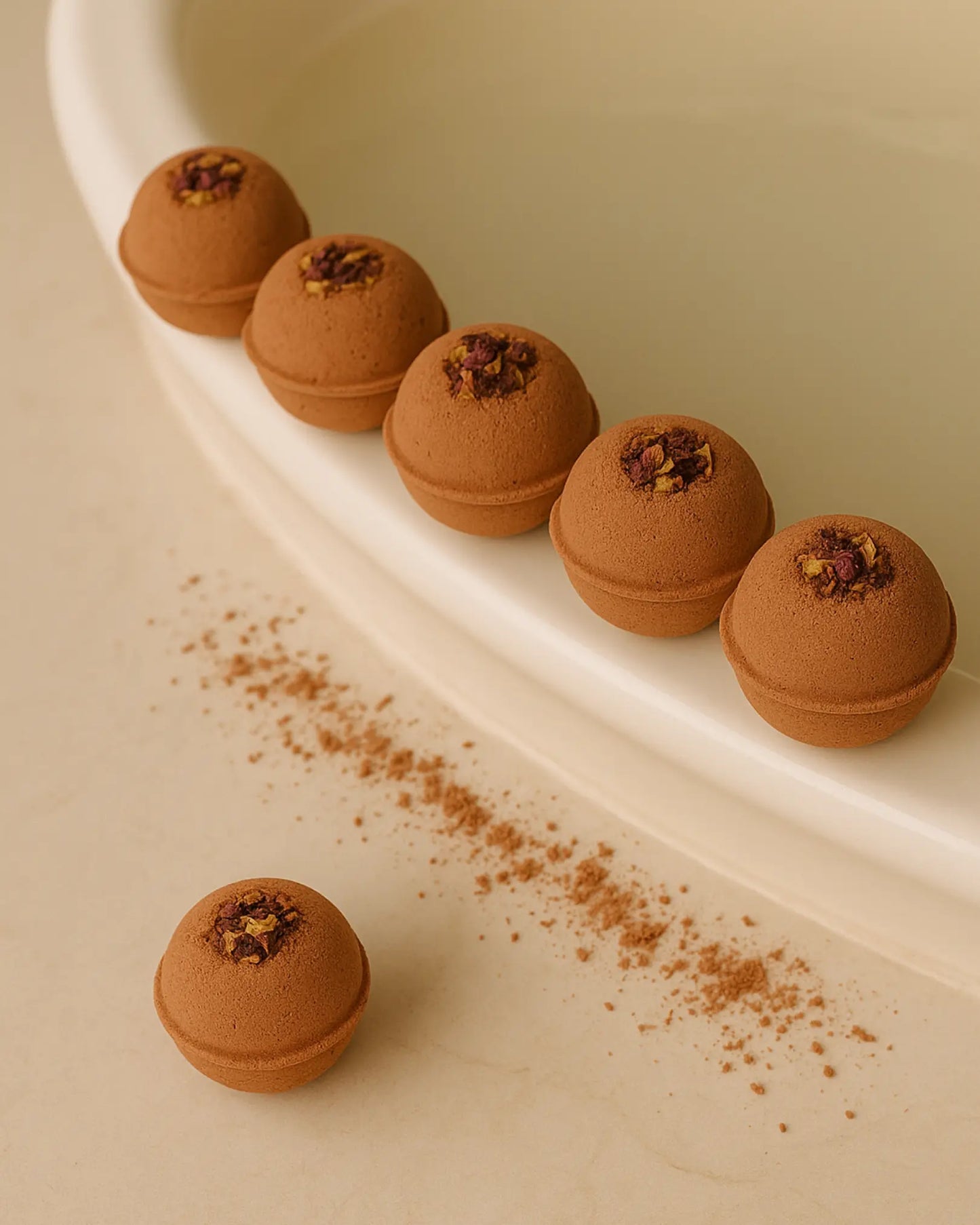 Six brown Deos Co. Aphrodite's Sphere bath bombs with dried flowers on a beige background 6-pack bath bomb set