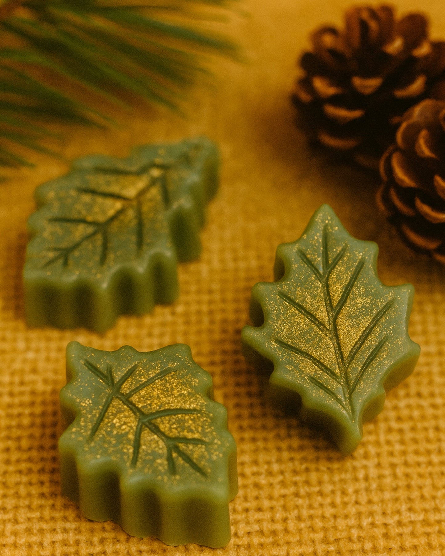 Set of Elysian Leaf botanical soaps by DEOS Co., inspired by Greek botanicals — featuring festive green leaves with golden shimmer, pine and orange aroma, and pure natural craftsmanship