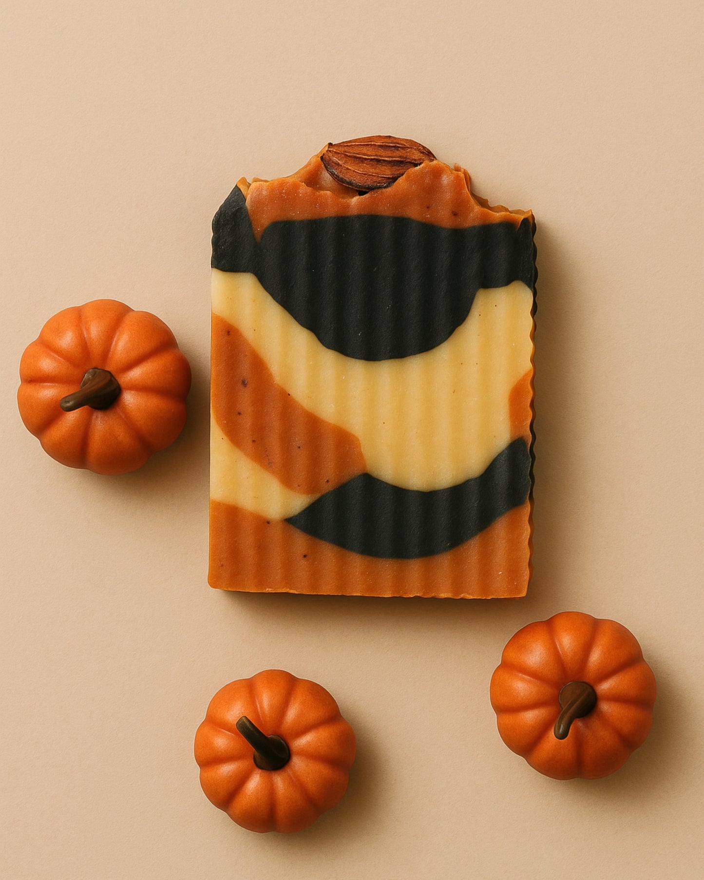 Bar of soap with pumpkin pattern surrounded by small pumpkins on a beige background by DEOS Co. soap brand