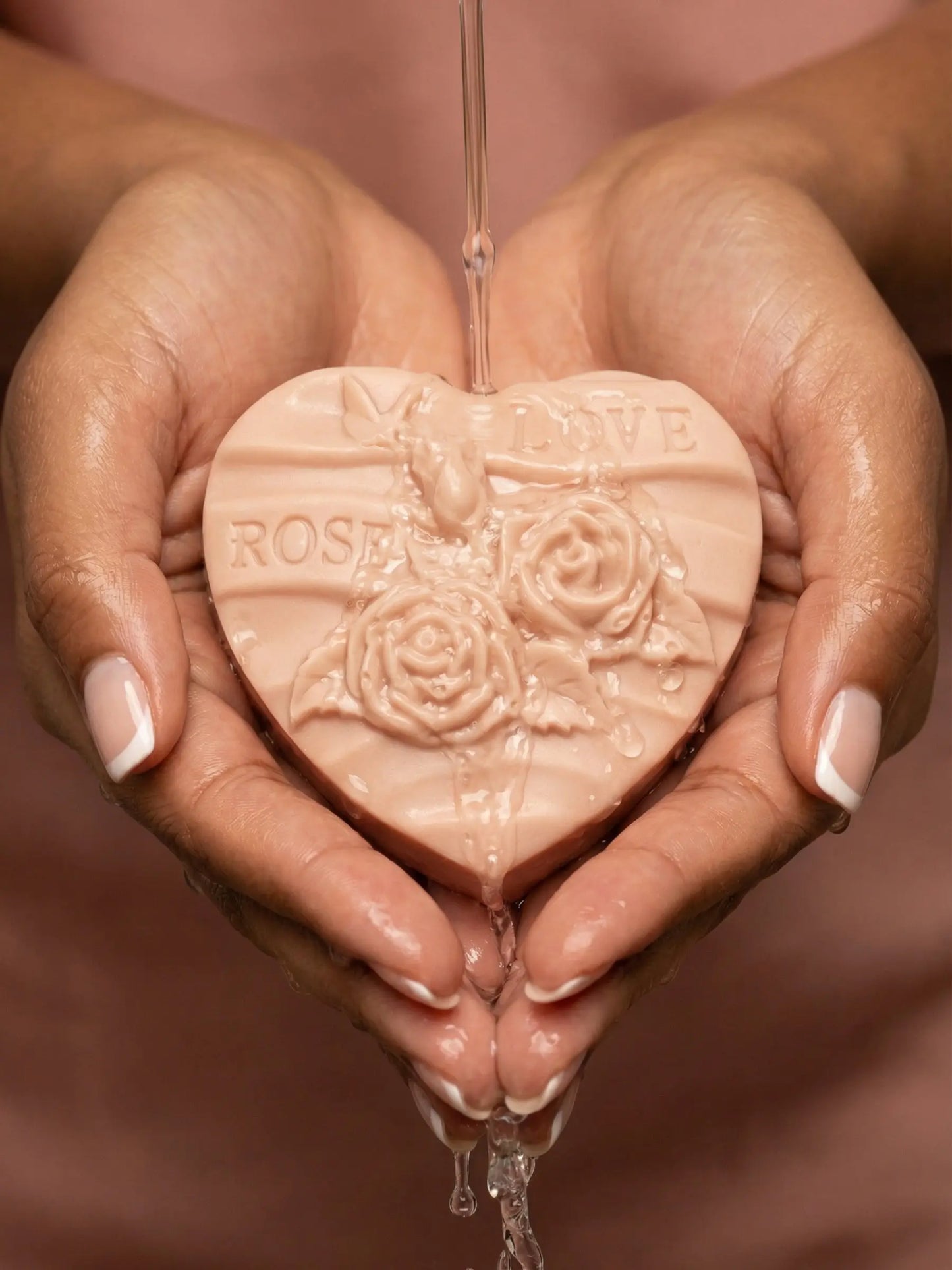 Hands holding RosƩlia heart-shaped rose soap with botanical engraving, natural rose geranium and vanilla cleansing bar from Deos Co.