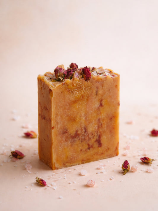 Aphrodite’s Glow rose geranium soap by DEOS Co., handcrafted olive oil soap made with organic olive oil and rose geranium, sculptural botanical bar photographed in warm natural light.