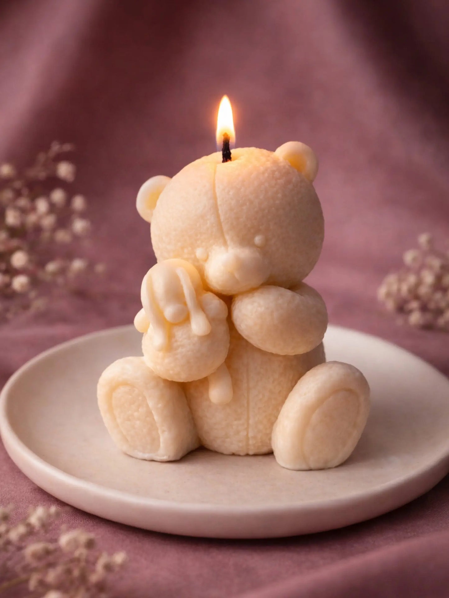 Lit vanilla soy Elior teddy bear candle creating a warm romantic atmosphere on ceramic plate by DEOS CO