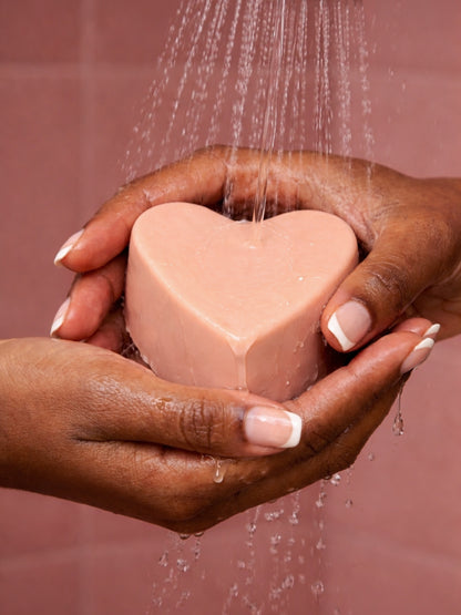 Luxury heart-shaped soap by DEOS Co. with rose geranium and vanilla, AGĀPE natural soap under running water Valentine's Day