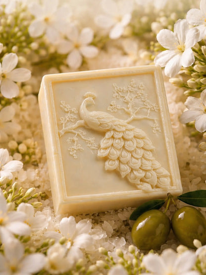 Jasmine olive oil soap with peacock design by DEOS Co., surrounded by white jasmine blossoms and green olives, luxury natural soap bar