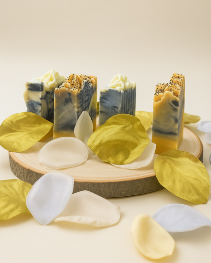 Collection of handmade charcoal soaps on a wooden board with leaves and petals.
