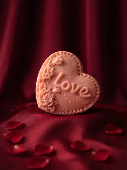Heart-shaped rose geranium and vanilla soap with 'love' text on a red fabric background. Valentine's Day gift Soap by DEOS CO with rose geranium and vanilla flavour