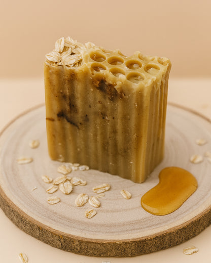 Bar of Melia Therion soap with honeycomb texture and oats on a wooden surface