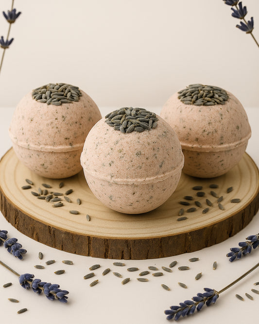 Three Nardus Sphere bath bombs by DEOS Co. with lavender flower seed toppings on a wooden stand, surrounded by lavender flowers and seeds.