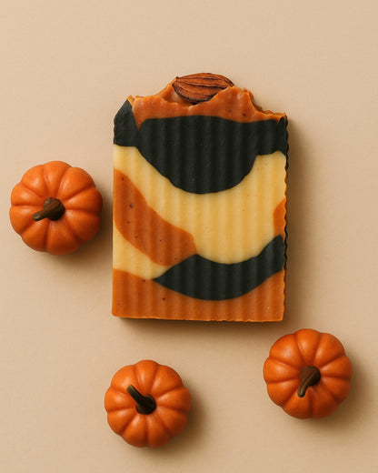 Bar of soap with pumpkin pattern surrounded by small pumpkins on a beige background by DEOS Co. soap brand