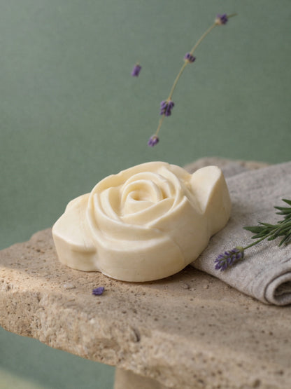 The Anthéa by DEOS CO., an ivory rose-shaped bar soap made with pure olive oil and lavender, displayed on natural stone