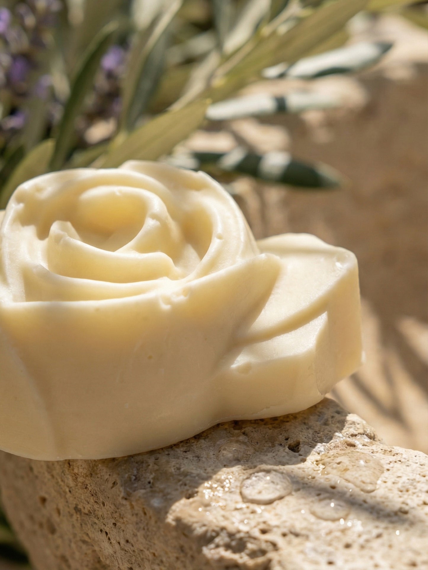 The Anthéa by DEOS CO., an ivory rose-shaped bar soap made from pure olive oil and lavender essential oil, is surrounded by lavender