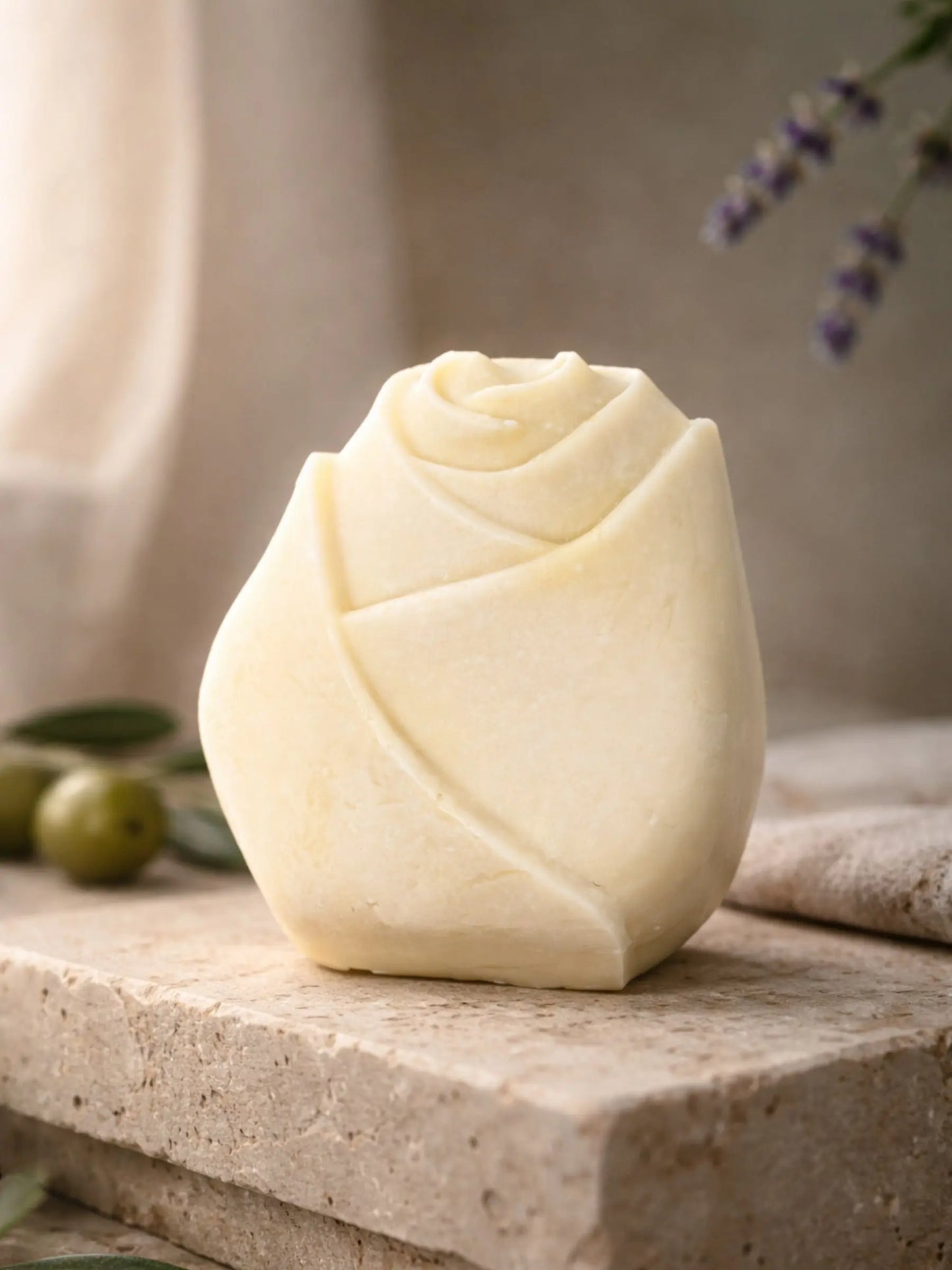 Handcrafted olive oil lavender soap shaped like a rose bud, displayed on natural stone by DEOS CO. - The Bud